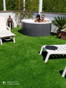 twee mensen in een bubbelbad in een tuin met gras bij Kristalex Pet Family Hotel in Cesenatico