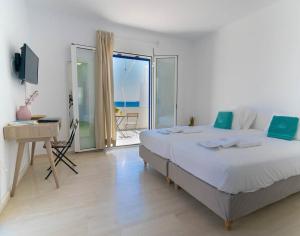 a bedroom with a bed and a desk and a balcony at Skinosummer in Paralia Agias Foteinis