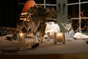 a table with glasses and candles and a vase with flowers at Hotel Villa Verdi in Knokke-Heist