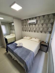 um quarto com uma cama grande e um cobertor azul em Quadra do mar. Lindo apto em Balneário Camboriú. em Balneário Camboriú