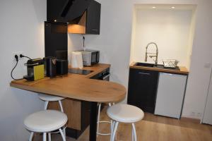 a kitchen with a table and two stools and a microwave at Exotika - appartement de charme, Rouen in Rouen