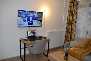 a room with a desk with a laptop and a tv on the wall at Exotika - appartement de charme, Rouen in Rouen