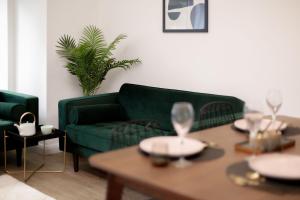 a living room with a green couch and a table at Moseley Gardens Fallowfield in Manchester