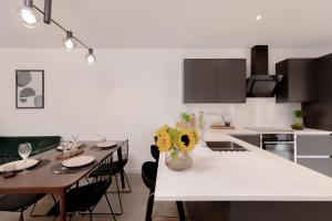 a kitchen with a table with chairs and a white counter top at Moseley Gardens Fallowfield in Manchester