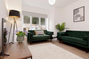 a living room with two green couches and a table at Moseley Gardens Fallowfield in Manchester