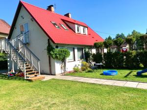 ein Haus mit einem roten Dach und einem Spielplatz in der Unterkunft Domek La Pergola in Łeba