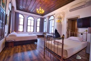 a bedroom with two beds and a tv and windows at Hotel Praga in Gjirokastër