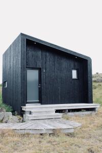a black building with a door in a field at iStay Cottages in Sandgerði