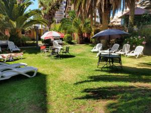 un grupo de sillas y mesas con sombrillas en un patio en San Remo Park Hotel en San Bernardo