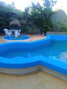 a blue swimming pool with a table and chairs at San Remo World Hotel in San Clemente del Tuyú