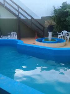 a blue swimming pool with a table and chairs at San Remo World Hotel in San Clemente del Tuyú