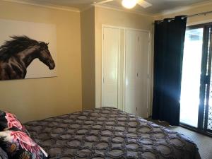 a bedroom with a painting of a horse on the wall at Bowral Bungalow in Bowral