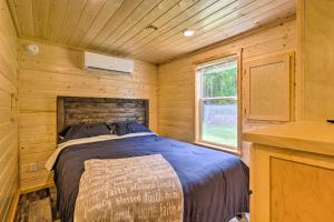 ein Schlafzimmer mit einem Bett in einer Holzhütte in der Unterkunft Quaint Mtn Cabin Tiny Living Near Big Adventure in Brevard