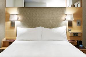 1 cama grande con sábanas blancas y 2 lámparas en Club Quarters Hotel Covent Garden Holborn, London, en Londres