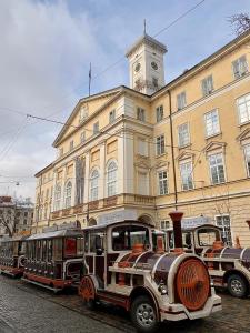 a row of train cars parked in front of a building at Apartments on Rynok Square in Lviv