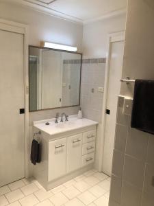 La salle de bains est pourvue d'un lavabo et d'une douche avec un miroir. dans l'établissement Bowral Bungalow, à Bowral