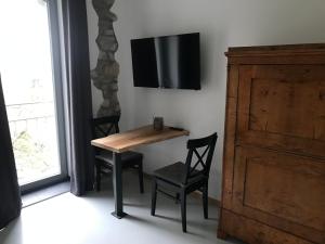mesa con 2 sillas y TV en la pared en Gästehaus Lausnitz Zimmer, en Lausnitz