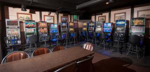 a row of slot machines in a room with tables and chairs at River Inn in Nipawin