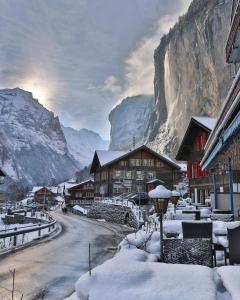 a snow covered village in front of a mountain at Hornerpub Apartments in Lauterbrunnen