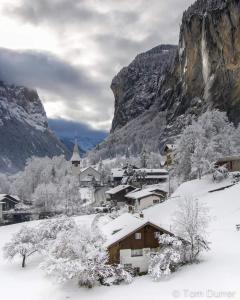 a village covered in snow with a mountain at Hornerpub Apartments in Lauterbrunnen