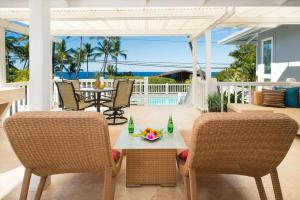 un patio con mesa, sillas y el océano en Kahaluu Sunset Hale en Kailua-Kona