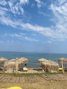 una spiaggia con alcuni ombrelloni di paglia e l'oceano di Sanni Beach Salonikiou a Akti Salonikiou