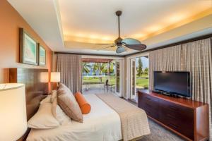 a bedroom with a bed and a flat screen tv at Keauhou Gardens Penthouse 22B at Kona Coast Resort in Kailua-Kona