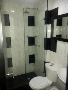 a bathroom with a toilet and a glass shower at Hotel Feria Nova in Bogotá