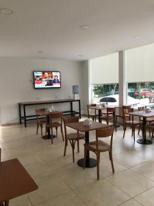 a restaurant with tables and chairs and a flat screen tv at Hotel Davinci in San Bernardo