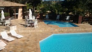 a swimming pool with chairs and a table and a swimming pool at CASA COM 4 QUARTO EM BUZIOS - 2 SUITES - Perto de Tudo in Búzios