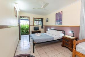 a bedroom with a bed and a desk and a television at Woolshed Eco Lodge in Hervey Bay