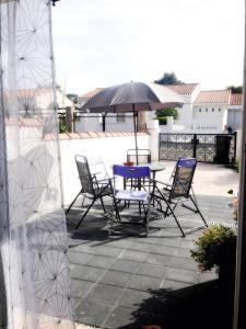 una mesa y sillas con una sombrilla en el patio en Halte cosy au porte de Bordeaux, en Tresses