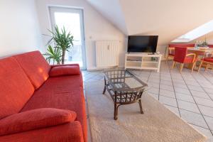 a living room with a red couch and a table at Ferienwohnung Burghausen in Unterneukirchen