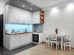 uma cozinha com armários brancos e uma mesa com cadeiras em Apartamentylove - Apartament Kiliński em Lódź