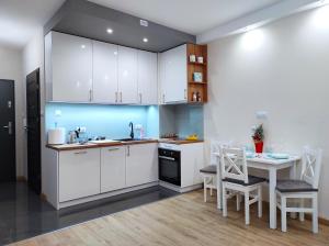 a kitchen with a table and chairs and a refrigerator at Apartamentylove - Apartament Kiliński in Łódź