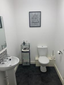La salle de bains est pourvue de toilettes blanches et d'un lavabo. dans l'établissement Kay's Place - Modern 3 Bed, à Manchester