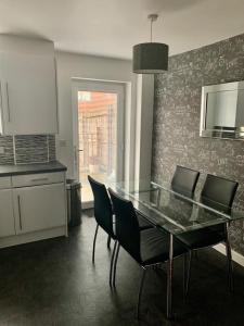 cocina con mesa de cristal y sillas en una habitación en Kay's Place - Modern 3 Bed, en Mánchester