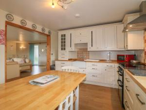 uma cozinha com armários brancos e um balcão de madeira em Clovermead Cottage em Willington