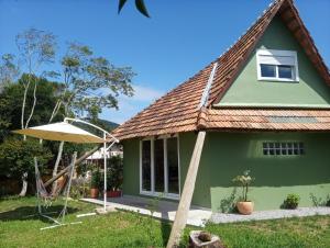 una casa verde con un paraguas en el patio en Vila Verde Suites en Florianópolis