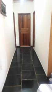 a hallway with a door and a black tile floor at Casa Costa Verde-Muriqui in Vila Muriqui