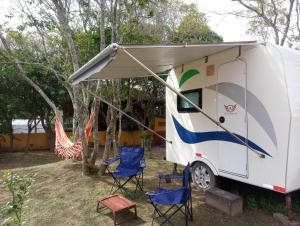 an rv with chairs and a tent at Vila Verde Suites in Florianópolis