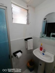 a white bathroom with a sink and a mirror at Asiriq Wasi Casita de huéspedes in Cusco