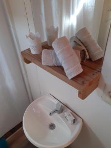 a bathroom with a sink and a shelf with towels at Las Luciernagas Posada de Mar in La Pedrera