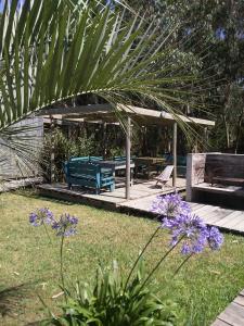 a garden with a blue bench and some purple flowers at Las Luciernagas Posada de Mar in La Pedrera