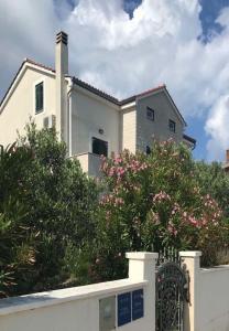 ein weißes Haus mit rosa Blumen hinter einem Zaun in der Unterkunft Apartments Azur - 10 m from sea in Ilovik