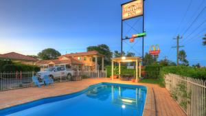 a swimming pool in front of a house with a sign at Country Roads Motor Inn in Goondiwindi