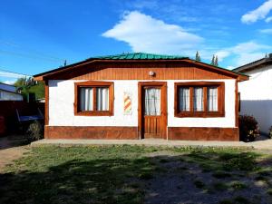 una pequeña casa con una puerta de madera en un patio en Los Dos Pinos en El Calafate