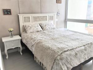 um quarto branco com uma cama, uma mesa de cabeceira e uma janela em Concón Costa de Montemar Departamento, 3 dormitorios em Concón mais 37 fotografias