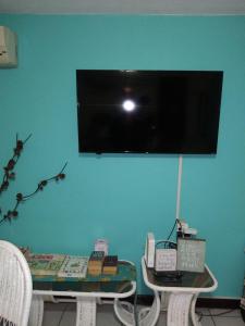 een televisie op een blauwe muur met een tafel en stoelen bij Cool's 1 bedroom Beach & Garden View in Ocho Rios