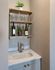 La salle de bains est pourvue d'un lavabo et de verres à vin sur une étagère. dans l'établissement Fireside Inn on Moonstone Beach, à Cambria